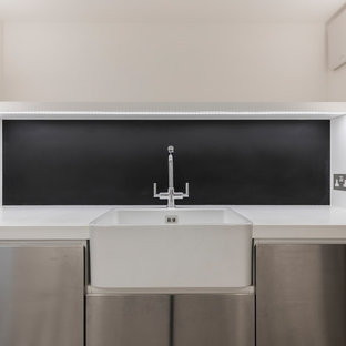 Imagen de lavadero multiusos y de galera, tradicional renovado, con fregadero sobremueble, armarios con paneles lisos, puertas de armario en acero inoxidable, encimera de acrílico, paredes blancas, suelo de baldosas de porcelana, lavadora y secadora juntas y suelo gris