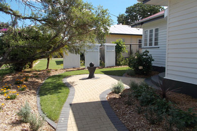 Photo of a mid-sized traditional front yard partial sun garden for spring in Brisbane with a garden path and concrete pavers.