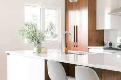 Design ideas for a mid-sized midcentury galley eat-in kitchen in Calgary with an undermount sink, flat-panel cabinets, medium wood cabinets, quartzite benchtops, white splashback, subway tile splashback, stainless steel appliances, light hardwood floors, with island, brown floor and white benchtop.