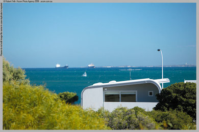 Photo of a mid-sized contemporary two-storey exterior in Perth with metal siding and a flat roof.