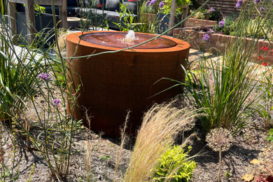 Photo of a large country back full sun garden for summer in Buckinghamshire with a water feature, decorative stones and a wood fence.