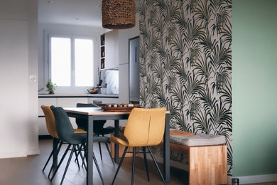 Réalisation d'une salle à manger ouverte sur le salon design avec un mur vert et sol en stratifié.