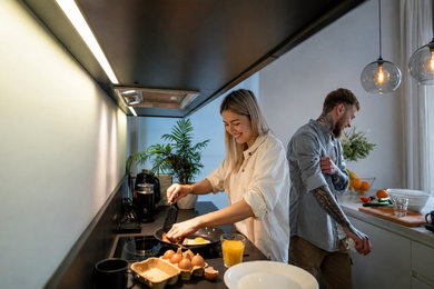 Eat-in kitchen - small modern galley eat-in kitchen idea in Edmonton with flat-panel cabinets, black cabinets, quartz countertops, black backsplash, quartz backsplash, black appliances, an island and black countertops