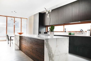This is an example of a mid-sized contemporary single-wall open plan kitchen with an undermount sink, flat-panel cabinets, dark wood cabinets, marble benchtops, window splashback, stainless steel appliances, concrete floors, with island and grey floor.