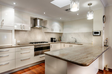 Mid-sized contemporary u-shaped open plan kitchen in Perth with a double-bowl sink, white cabinets, marble benchtops, beige splashback, stone tile splashback, stainless steel appliances, dark hardwood floors and no island.