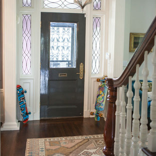 Eklektisk inredning av en mellanstor foajé, med vita väggar, mörkt trägolv, en dubbeldörr, metalldörr och rosa golv