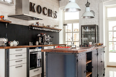 Photo of an industrial galley kitchen in Other with flat-panel cabinets, white cabinets, black splashback and with island.
