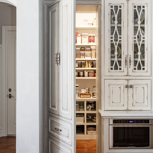 Large traditional kitchen pantry photos - Example of a large classic u-shaped medium tone wood floor and brown floor kitchen pantry design in Jacksonville with a farmhouse sink, beaded inset cabinets, white cabinets, quartz countertops, white backsplash, stone slab backsplash, stainless steel appliances and an island