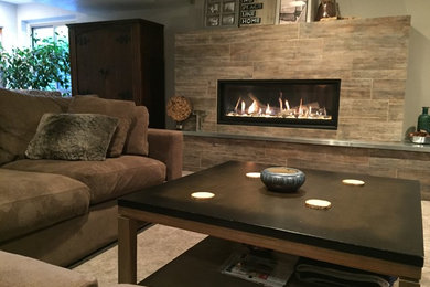 This is an example of a large contemporary walk-out basement in Denver with beige walls, a ribbon fireplace, a tile fireplace surround, carpet and beige floor.
