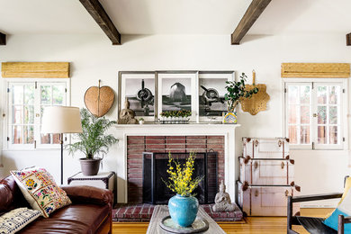 This is an example of a large eclectic enclosed living room in Los Angeles with a library, white walls, medium hardwood floors, a standard fireplace, a brick fireplace surround and a built-in media wall.