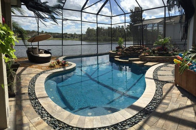 Inspiration for a mid-sized transitional indoor custom-shaped pool in Orlando with a hot tub and natural stone pavers.