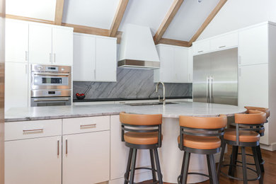 Inspiration for a mid-sized transitional u-shaped medium tone wood floor, brown floor and vaulted ceiling open concept kitchen remodel in Other with an undermount sink, flat-panel cabinets, white cabinets, quartzite countertops, gray backsplash, marble backsplash, stainless steel appliances, an island and gray countertops