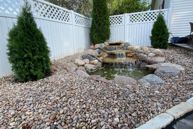 Ejemplo de jardín retro de tamaño medio en verano en patio trasero con fuente, exposición parcial al sol, adoquines de piedra natural y con vinilo