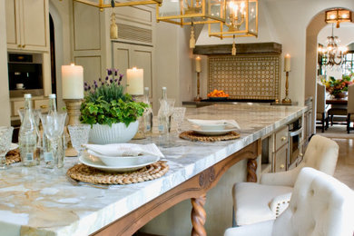 Example of a large tuscan u-shaped travertine floor, beige floor and coffered ceiling eat-in kitchen design in Orange County with a triple-bowl sink, shaker cabinets, beige cabinets, quartz countertops, beige backsplash, terra-cotta backsplash, stainless steel appliances, two islands and gray countertops