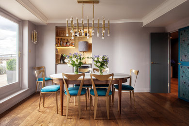 Photo of a mid-sized contemporary dining room in London with medium hardwood floors, brown floor and purple walls.