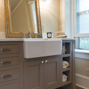 Aménagement d'une salle de bain principale craftsman de taille moyenne avec une grande vasque, un placard à porte plane, des portes de placard grises, un plan de toilette en granite, un mur beige et un sol en bois brun.