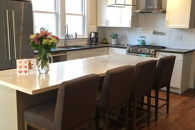 Inspiration for a mid-sized contemporary l-shaped dark wood floor and brown floor eat-in kitchen remodel in Philadelphia with an undermount sink, shaker cabinets, white cabinets, white backsplash, subway tile backsplash, stainless steel appliances, an island and white countertops