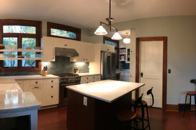 This is an example of an arts and crafts kitchen pantry in Seattle with an undermount sink, shaker cabinets, white cabinets, onyx benchtops, green splashback, glass tile splashback, stainless steel appliances, medium hardwood floors, with island and white benchtop.