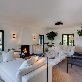 Inspiration for a mediterranean living room in Los Angeles with white walls, dark hardwood flooring, a standard fireplace, a plastered fireplace surround, a built-in media unit and brown floors.