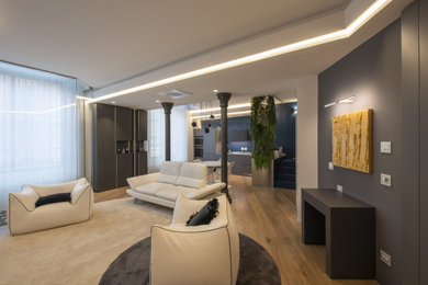 Esempio di un soggiorno di medie dimensioni con pareti beige, pavimento in legno verniciato, TV a parete, pavimento marrone e soffitto ribassato