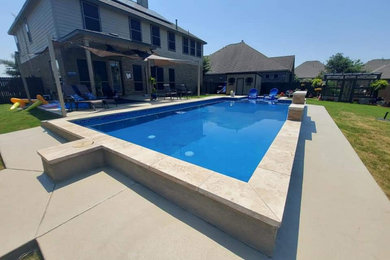 Modelo de piscina alargada moderna de tamaño medio rectangular en patio trasero con paisajismo de piscina, privacidad y losas de hormigón