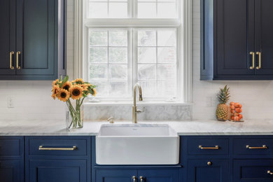 Example of a large classic l-shaped dark wood floor and brown floor eat-in kitchen design in New York with a farmhouse sink, flat-panel cabinets, blue cabinets, marble countertops, white backsplash, marble backsplash, paneled appliances, an island and white countertops