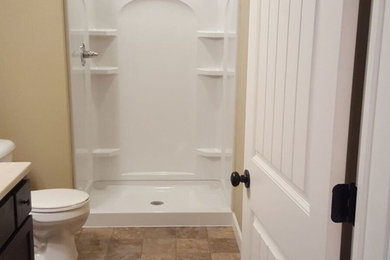 Example of a mid-sized classic 3/4 travertine floor and beige floor alcove shower design in San Diego with shaker cabinets, dark wood cabinets, beige walls, an integrated sink, marble countertops and a one-piece toilet