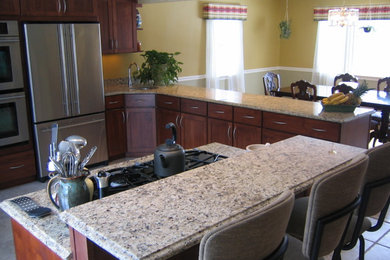 Eat-in kitchen - mid-sized traditional u-shaped ceramic tile and beige floor eat-in kitchen idea in Boston with an undermount sink, recessed-panel cabinets, medium tone wood cabinets, granite countertops, stainless steel appliances, an island, brown backsplash and stone slab backsplash