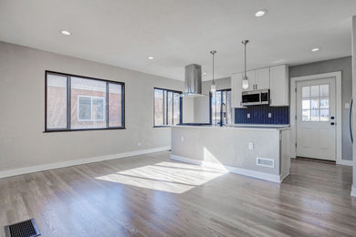 Example of a mid-sized u-shaped medium tone wood floor and gray floor eat-in kitchen design in Denver with an undermount sink, shaker cabinets, white cabinets, granite countertops, black backsplash, cement tile backsplash, stainless steel appliances, an island and white countertops