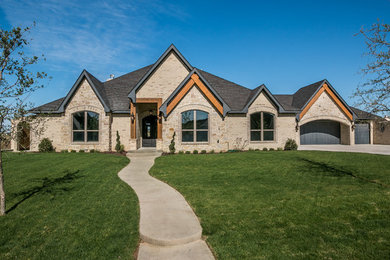 Large trendy beige two-story brick gable roof photo in Dallas