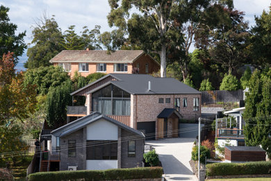 Mid-sized modern two-storey house exterior in Hobart with a gable roof, a metal roof and a grey roof.