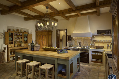 Example of a tuscan kitchen pantry design in Phoenix with beige backsplash, stainless steel appliances and an island