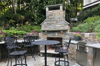 Example of a mid-sized mountain style backyard stone patio design in New York with a fireplace