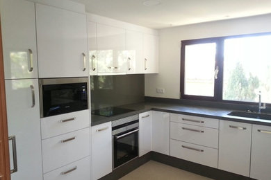 This is an example of a mid-sized transitional l-shaped separate kitchen in Other with a single-bowl sink, flat-panel cabinets, white cabinets, grey splashback, stainless steel appliances and no island.