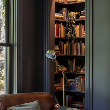 Built-in bookcase with leather chair in dark-walled sitting room