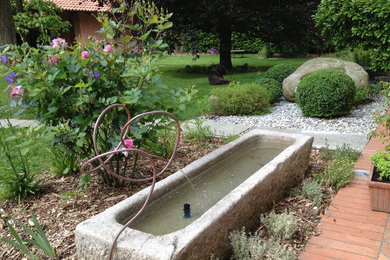 Immagine di un giardino country esposto in pieno sole di medie dimensioni e davanti casa in primavera con ghiaia e fontane