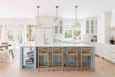 Example of a large transitional light wood floor kitchen design in Other with a farmhouse sink, shaker cabinets, blue cabinets, quartz countertops, quartz backsplash, paneled appliances and an island
