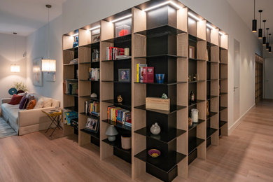 Modelo de biblioteca en casa abierta y blanca y madera contemporánea de tamaño medio de obra con paredes blancas y suelo de madera clara