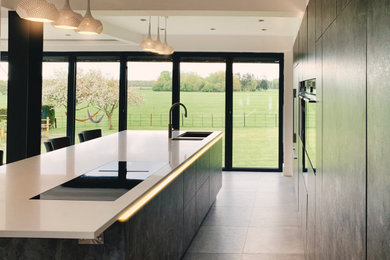 Photo of a medium sized contemporary galley kitchen/diner in Other with flat-panel cabinets, black cabinets, quartz worktops, an island and white worktops.