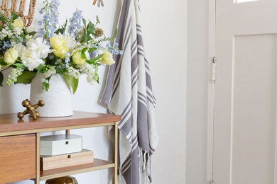 Small trendy painted wood floor and brown floor entryway photo with white walls and a white front door