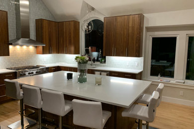 Example of a large minimalist u-shaped light wood floor eat-in kitchen design in Dallas with an undermount sink, flat-panel cabinets, medium tone wood cabinets, quartz countertops, gray backsplash, mosaic tile backsplash, stainless steel appliances, an island and white countertops