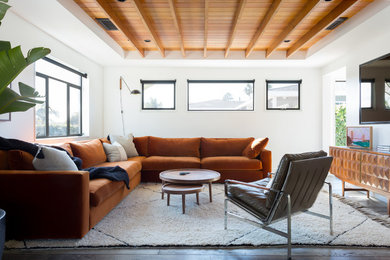 Example of a trendy dark wood floor living room design in Orange County with white walls and a wall-mounted tv