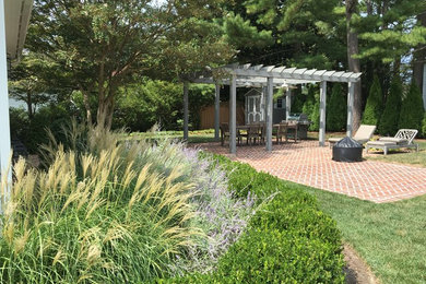 Mid-sized elegant backyard brick patio photo in Other with a fire pit and a pergola
