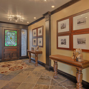 Bild på en stor eklektisk foajé, med gula väggar, skiffergolv, en enkeldörr och mellanmörk trädörr