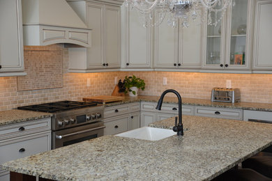 Example of a mid-sized arts and crafts l-shaped dark wood floor eat-in kitchen design in Detroit with a farmhouse sink, recessed-panel cabinets, black cabinets, granite countertops, beige backsplash, stone tile backsplash, stainless steel appliances and an island