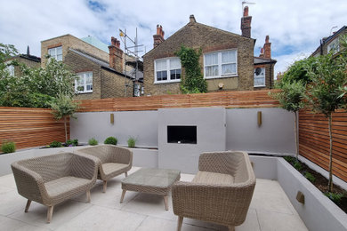 This is an example of a large modern courtyard patio in London with a fire feature.