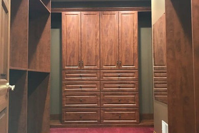 Inspiration for a large timeless gender-neutral carpeted walk-in closet remodel in Louisville with raised-panel cabinets and dark wood cabinets