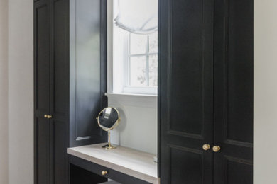 Foto de armario y vestidor unisex tradicional pequeño con a medida, armarios estilo shaker, puertas de armario negras, suelo de madera clara y papel pintado