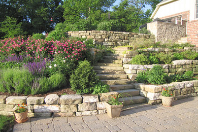 This is an example of a large partial sun front yard stone retaining wall landscape in St Louis for spring.