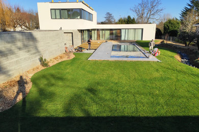 Réalisation d'un grand jardin design avec une exposition ensoleillée et des galets de rivière.